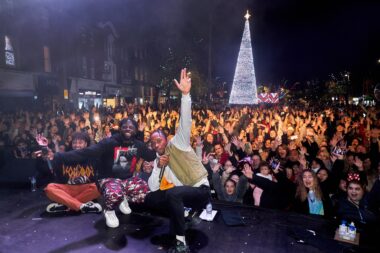 performers on stage with crowd behind them